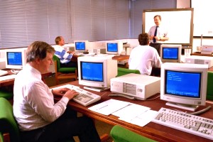 Foto de un grupo de personas en un aula informática, con un profesor.